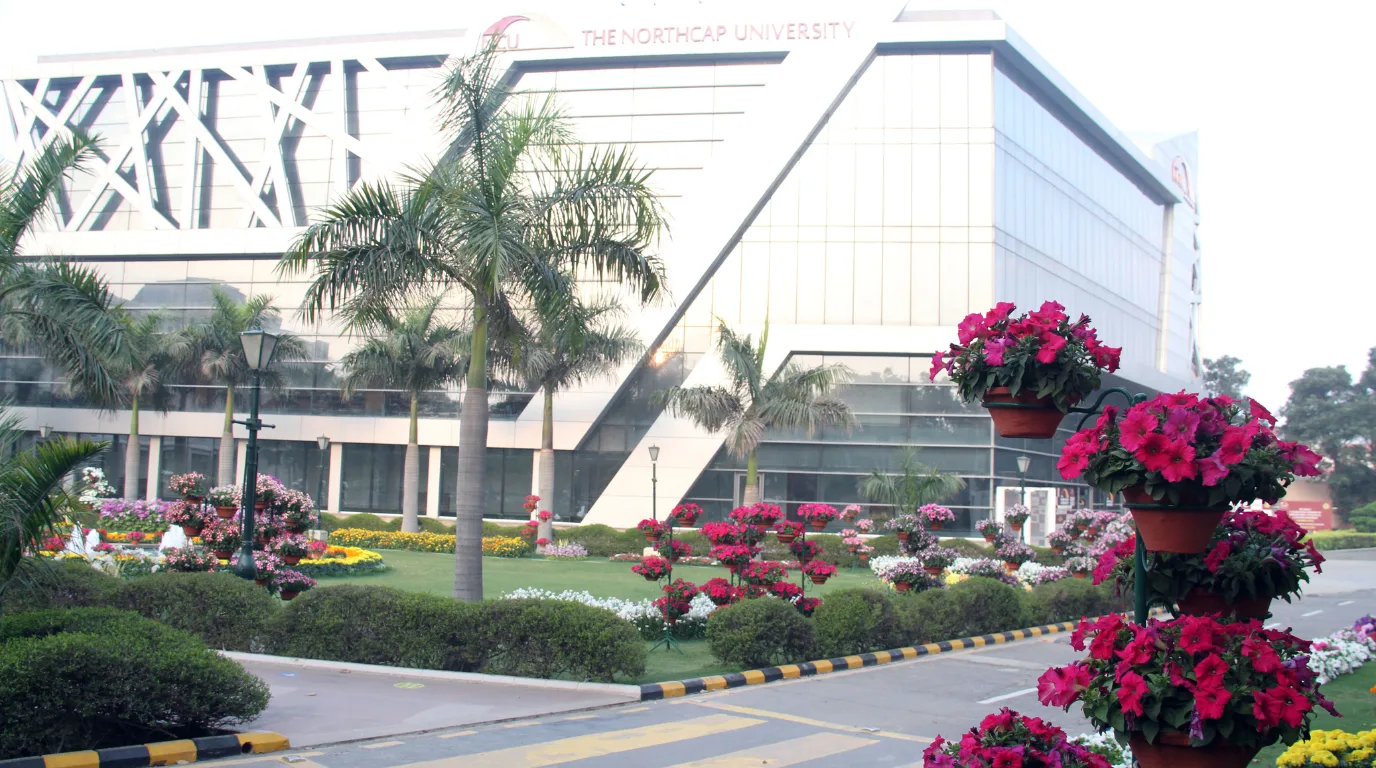 The NorthCap University modern glass-fronted building with geometric facade framed by palm trees